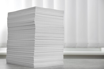 Stack of paper sheets on grey table. Space for text