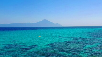 Aerial drone view from above to single sport kayak boat with 2 people. Touristic canoe summer sport activity in Mediterranean sea blue water on mountains background