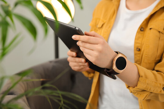 Woman With Tablet Wearing Smart Watch At Home, Closeup