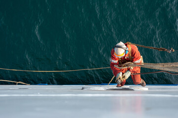 Seaman ship crew working aloft at height derusting and getting vessel ready for painting. - obrazy, fototapety, plakaty