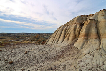 A rock formation in the Canadian Badlands. Banded sandstone rock formation is the focus with the badlands in soft focus beyond. 
