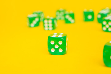 Green gaming dices on yellow background: one green dice with number five. Flat lay, place for text, top view. Table games concept, board game for the whole family, side view