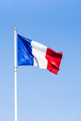 French flag waving in the wind on a sunny day.