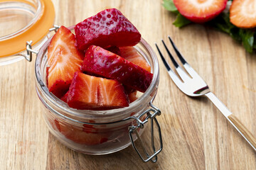 Fresh and natural strawberries (big strawberries) in a glass jar and a tendor. Foreground.