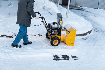 Man cleaning driveway with snow machines after a snow storm. Snow removal equipment working on the...