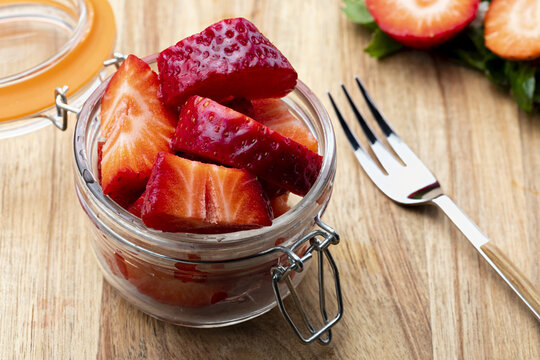 Fresh and natural strawberries (big strawberries) in a glass jar and a tendor. Foreground.