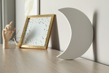 Crescent shaped night lamp on wooden shelf in child's room