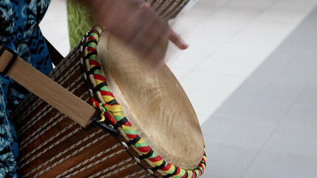 the hands of a male african american beat the drum