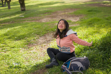 Obraz premium lifestyle portrait of young happy and beautiful Asian Chinese woman in pink sweater lying on green grass cheerful and excited playing outdoors enjoying carefree