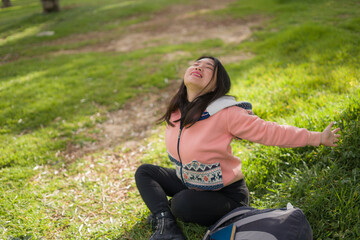 Fototapeta na wymiar lifestyle portrait of young happy and beautiful Asian Korean woman in pink sweater lying on green grass cheerful and excited playing outdoors enjoying carefree