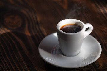 A cup of aromatic black coffee. Morning espresso or Americano coffee for breakfast in a beautiful cup. Wooden background. Couple with coffee. 