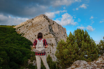 Fit female hiker with backpack standing on a rocky mountain ridge