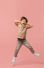 Fototapeta na wymiar Shouting. Happy, smiley little caucasian boy isolated on pink studio background with copyspace for ad. Looks happy, cheerful. Childhood, education, human emotions, facial expression concept.