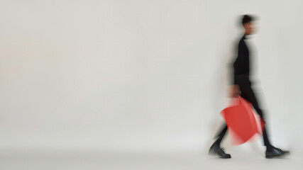 Blurred figure of man walking on light background