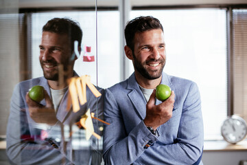 Businessman in conference room eating apple. Young businessman having healthy snack.