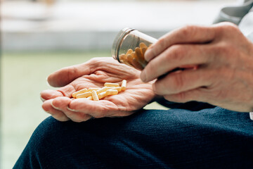 close up on the hands of an old man taking pills