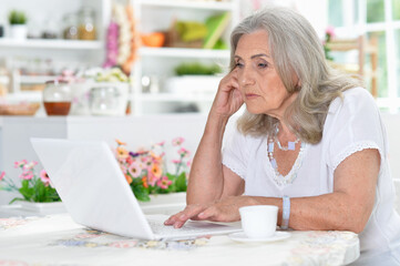 Obraz na płótnie Canvas Tired senior woman using laptop