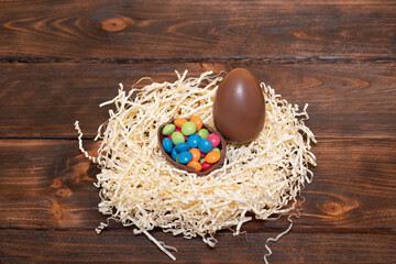 Easter chocolate eggs in a nest on a wooden background. Easter composition.
