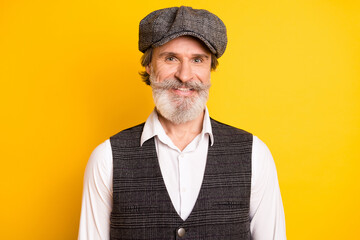 Photo of mature handsome man happy positive smile wear retro hat isolated over yellow color background