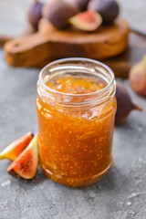 Glass jar with sweet fig jam on grunge background