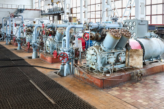 Interior element of chemical enterprise. Row of ammonia reciprocating compressors with cylinders and electric motor with control panel, with control devices and alarm systems.
