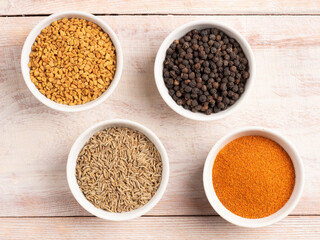 Spice red and black pepper, cumin, fenugreek in a white bowl on a light wooden background