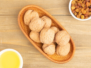 Raisins in a white bowl, walnuts, honey on brown wooden background