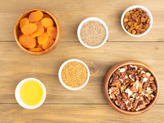 Raisins, walnuts, honey, dried apricot, cumin, fenugreek on brown wooden background