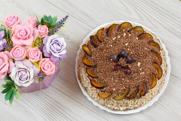 Obraz na płótnie Canvas Chocolate cake decorated with plums and flowers.