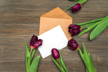 White paper and envelope for writing and tulip flowers on a wooden background, space for text