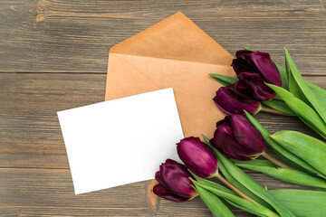 White paper and envelope for writing and tulip flowers on a wooden background, space for text