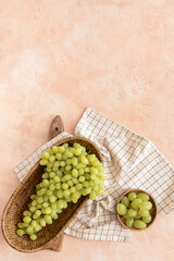 Basket with ripe green grapes on color background
