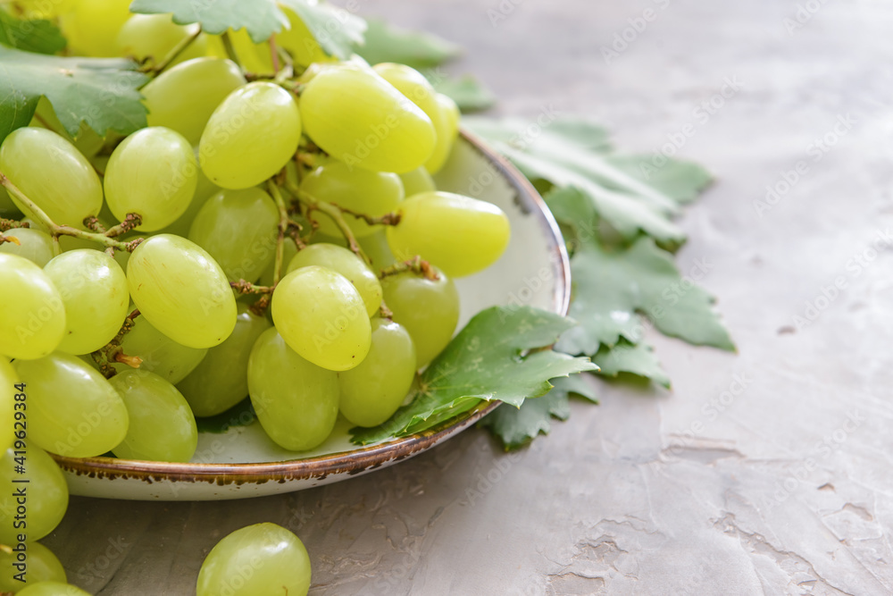 Wall mural Plate with ripe green grapes on grunge background, closeup