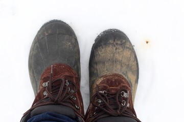 A close view of the dirty boots in the white snow.