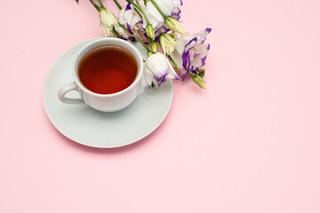 Purple flowers and a white coffee cup on a pink background. A beautiful banner with space to copy.