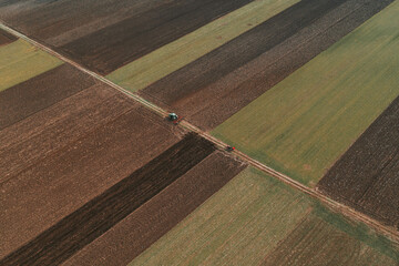 Aerial view of two farm tractors tilling in cultivated fields