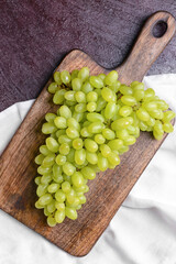 Board with ripe green grapes on dark color background