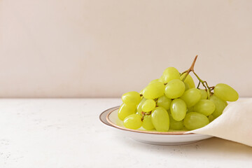 Plates with ripe green grapes on white background
