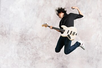 Portrait of a musician man jumps while playing on guitar