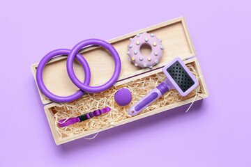 Box with different pet accessories on color background