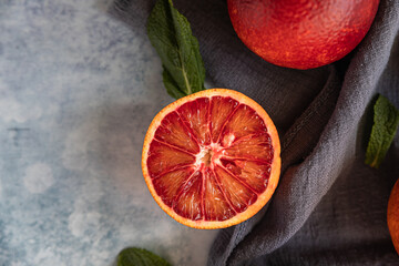 Cut in half blood Sicilian orange on blue concrete background. 