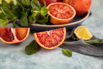 Red Sicilian oranges with limes and mint on blue background. Whole and sliced citrus.