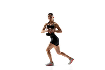 Fototapeta premium Dumbbells. Caucasian professional female athlete training isolated on white studio background. Muscular, sportive woman. Concept of action, motion, youth, healthy lifestyle. Copyspace for ad.