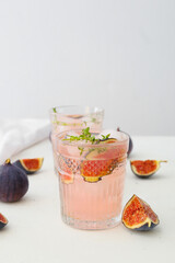 Glasses of tasty fig lemonade on light background