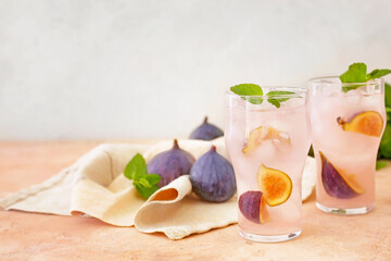 Glasses of tasty fig lemonade on color background