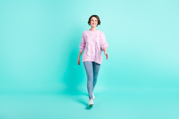 Full length photo of charming pretty young woman wear violet sweater walking isolated turquoise color background
