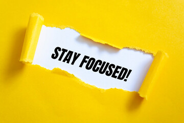 STAY FOCUSED word written behind torn paper.