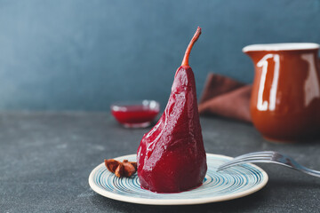 Plate of tasty poached pears in wine sauce on dark background