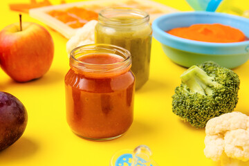 Jars with different baby food and ingredients on color background, closeup