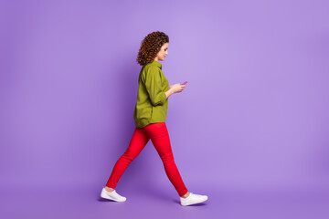 Fototapeta na wymiar Full size profile side photo of young attractive pretty beautiful girl go walk using smartphone isolated on violet color background